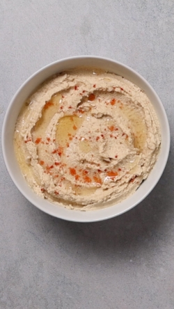 Scrape the hummus into a bowl and garnish with some avocado oil and paprika.
