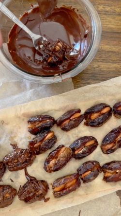 Your melted chocolate will now be mostly cooled and easier to work with. Coat each date in chocolate and place on parchment paper.