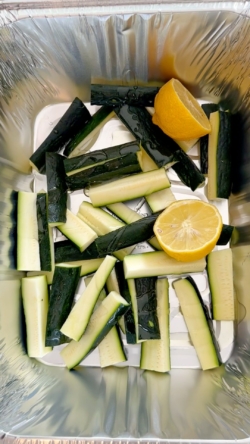 Place zucchini and lemon in an oven-safe pan of cookie sheet and coat with avocado oil and toss. Add salt and toss.