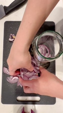While vinegar mixture is heating, slice 1-2 red onions thinly and add to clean, heat-safe glass jar with lid