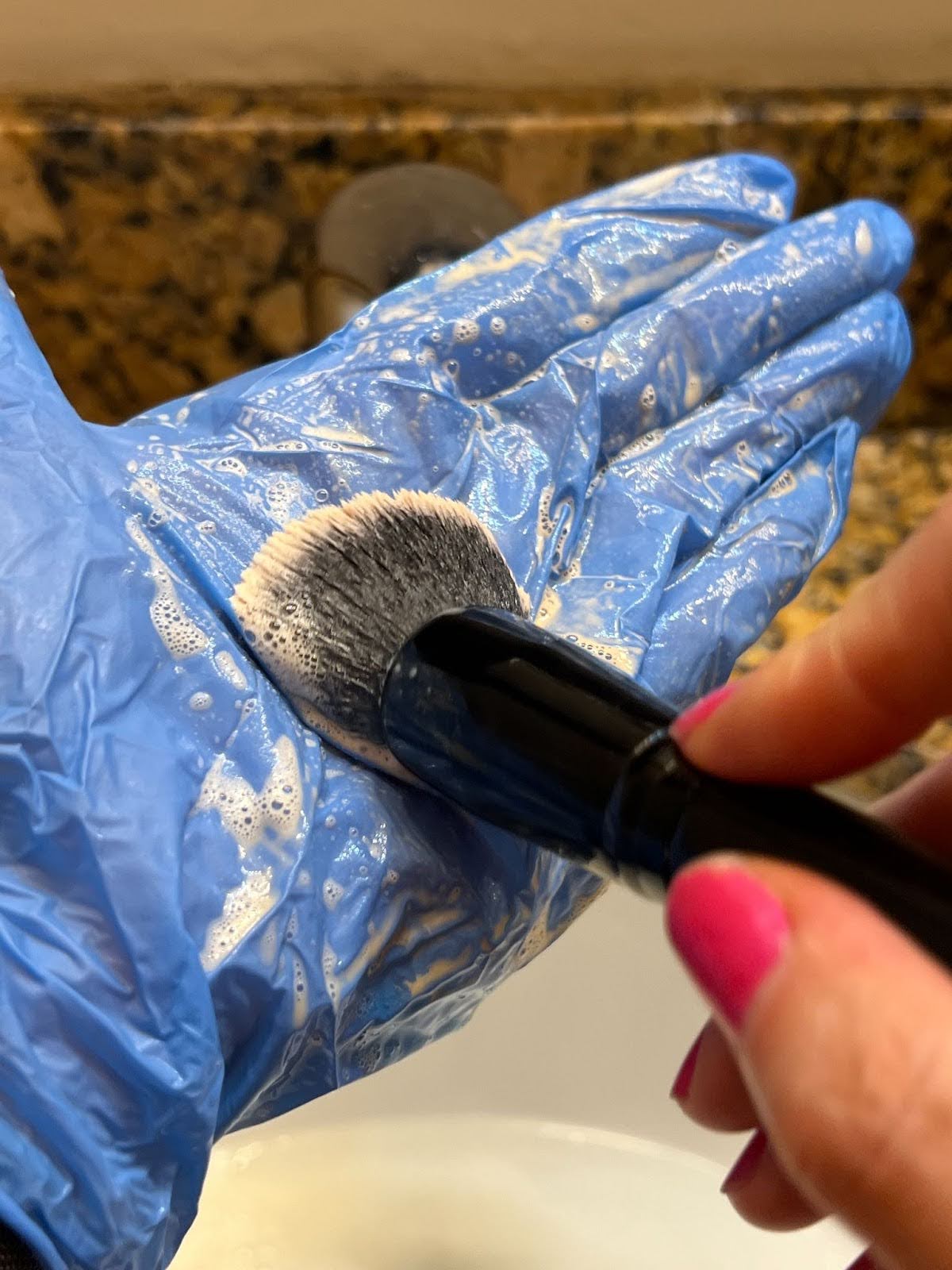 Gently massage the soap into the bristles by swirling the brushes on a silicone brush mat or the palm of your hand. If you have sensitive skin, wear a latex glove as shown.