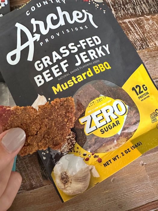 Picture of a single serving of Country Archer - Grass-Fed Beef Jerky Mustard BBQ in front of package. 