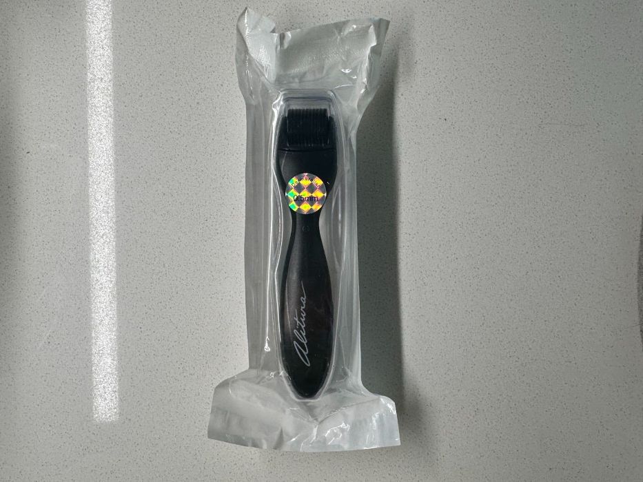 A derma roller in a sealed plastic packaging, featuring a black handle with the brand name "Altima" 
