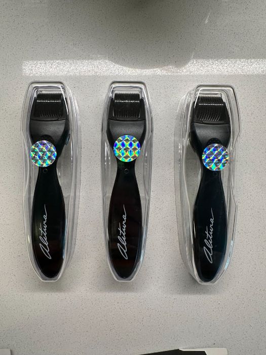 The image shows three identical derma rollers in packaging.